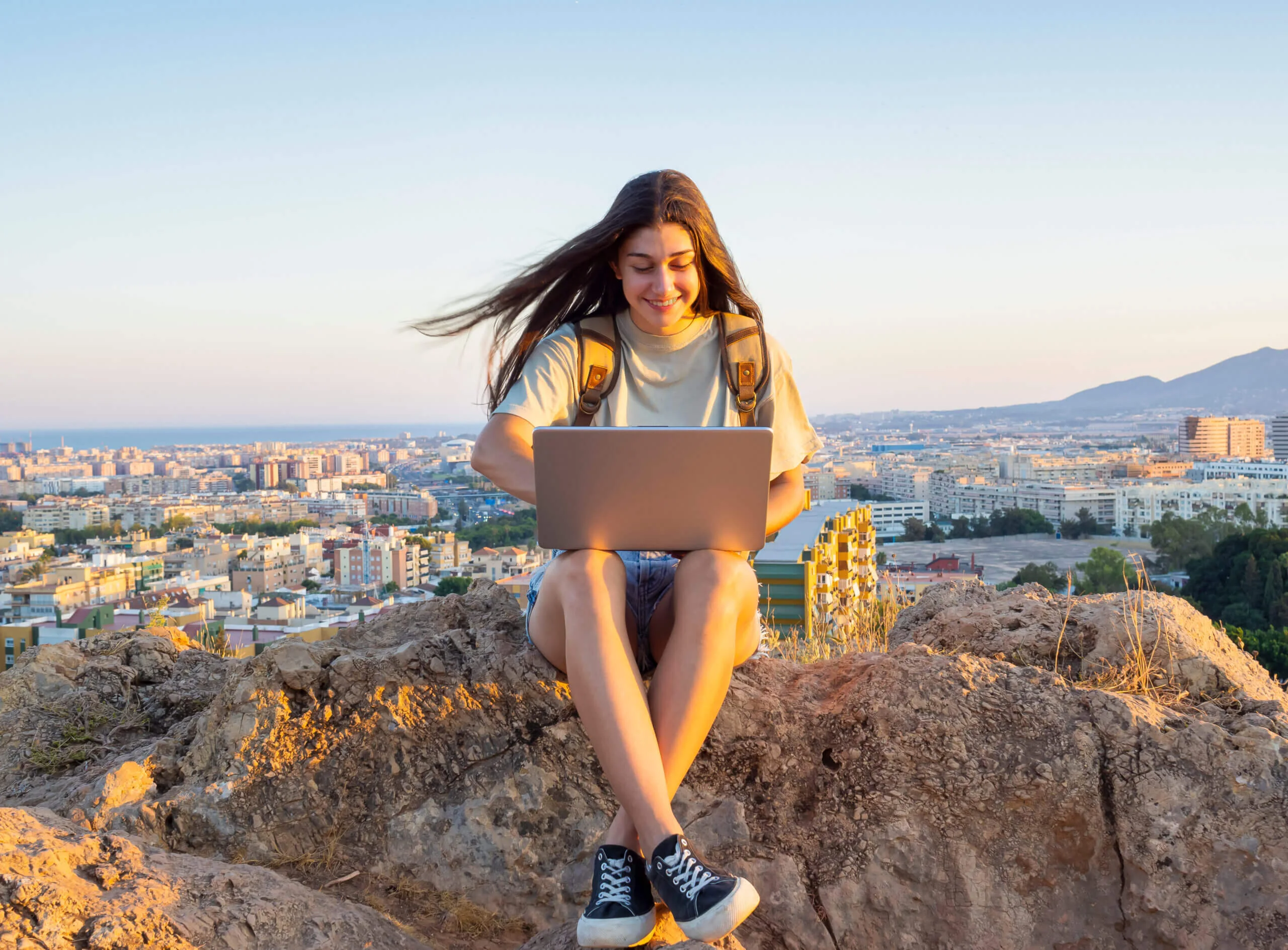 Nómada digital trabajando en remoto con un portátil y vistas a Málaga, España